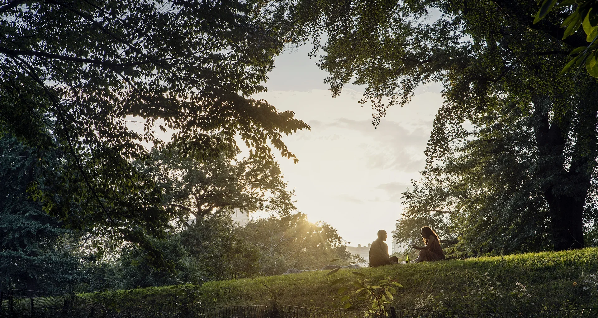 Two friends sitting in a park near The Strathmore luxury apartments in Manhattan.