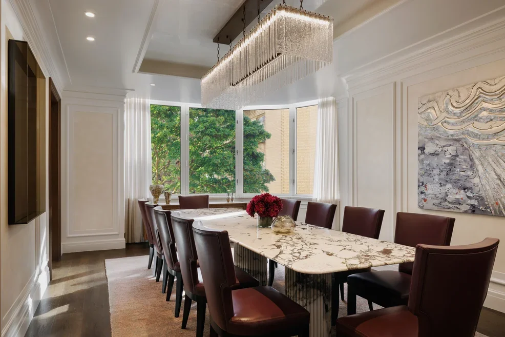 Well lit dining room with a long table, chairs and an overhead lighting fixture