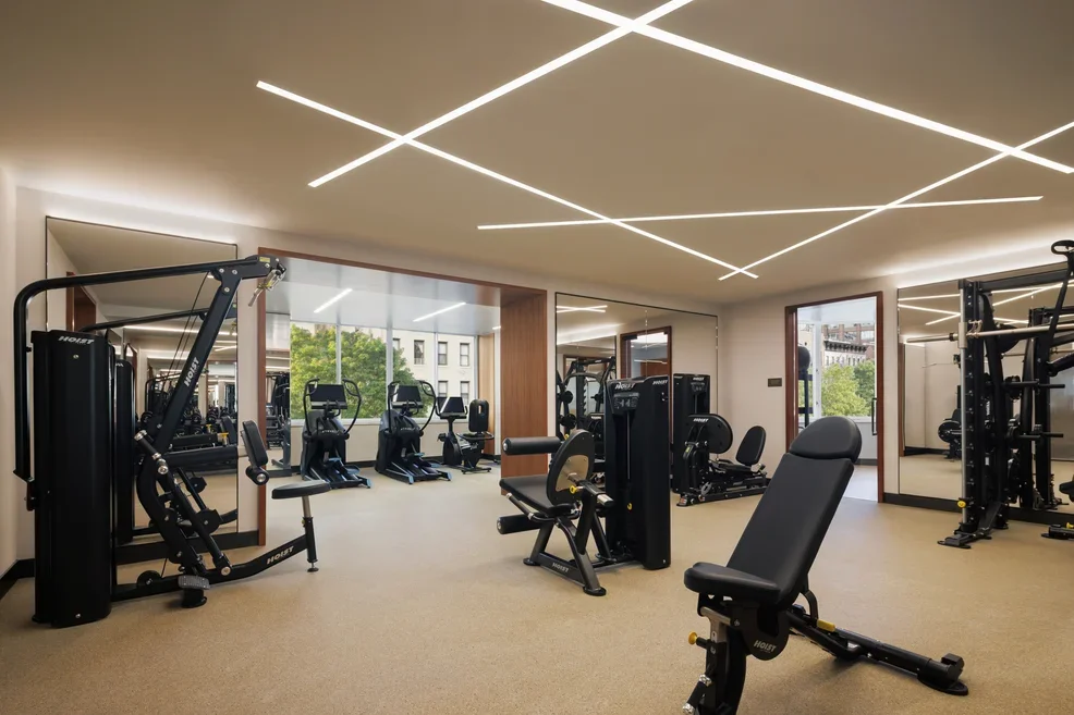 Fitness center with weights and exercise machines, one of The Strathmore NYC's luxury amenities.