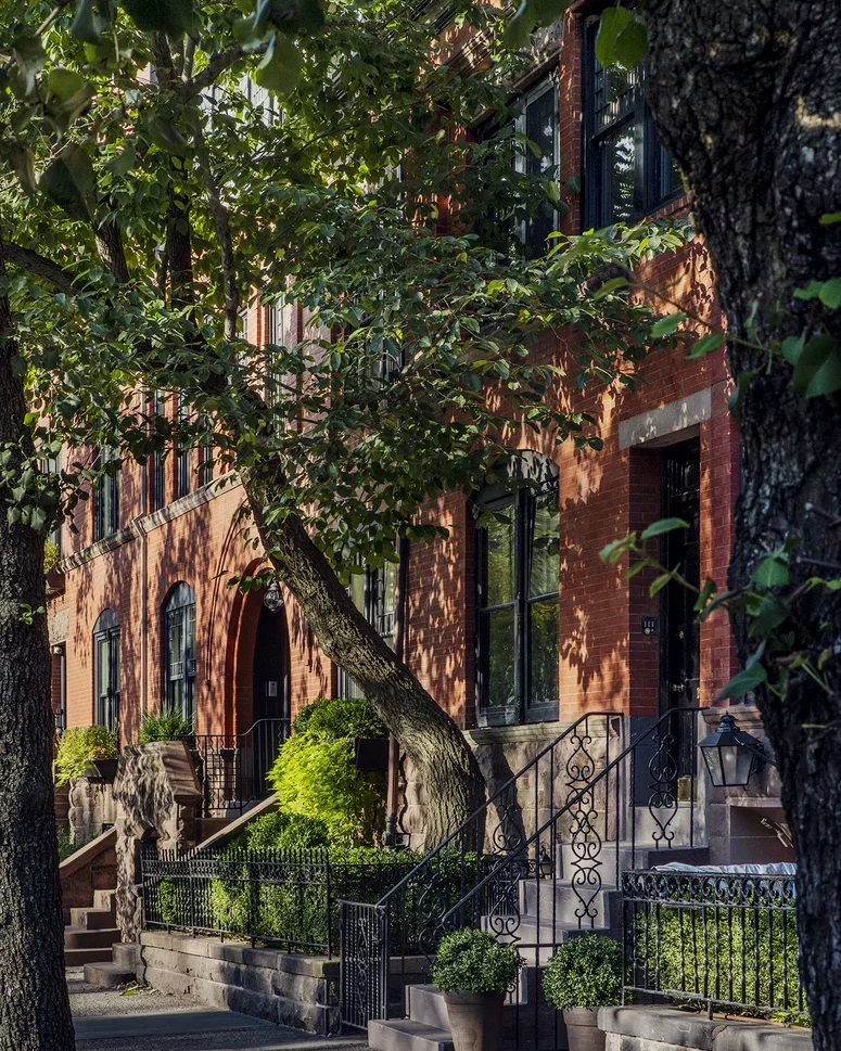 Tree-lined streetfront of the Strathmore luxury condos in Manhattan, with wrought-iron fences and railings, and classic exterior brickwork